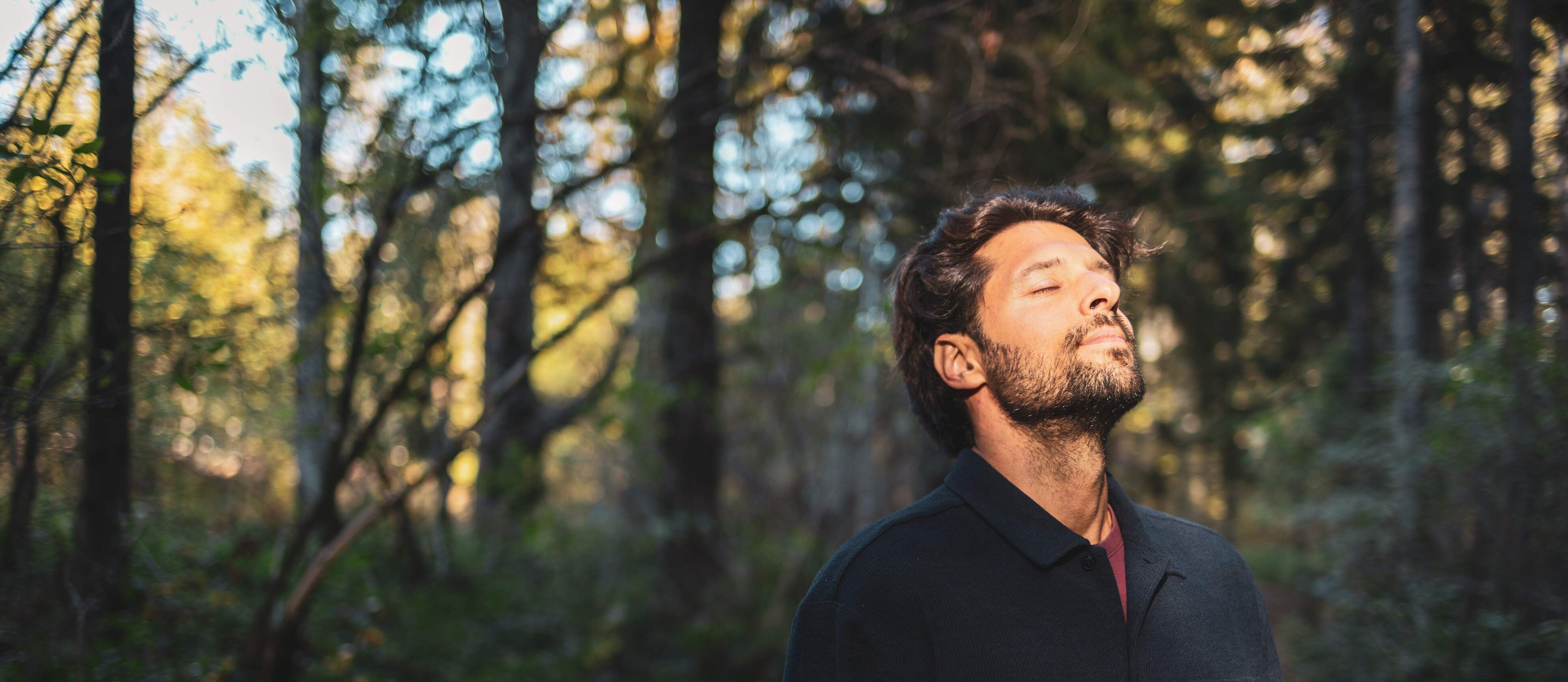Mann im Wald mit Sonne im Gesicht